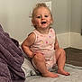 baby, barefoot, blanket, casual, child, curly_hair, cute, earrings, floor, happy, indoors, light_switch, mattress, pink_clothing, portrait, sitting, smiling, toddler, wall, young_child