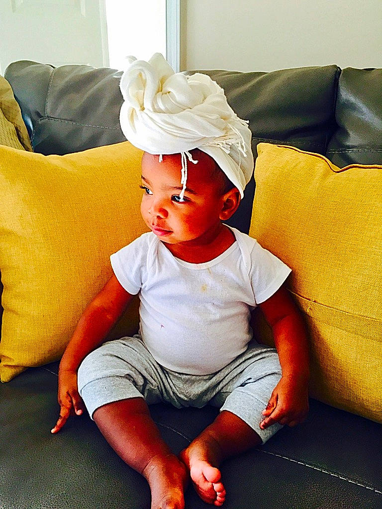 Anais Keller Robinson is registered to the contest to win money with this photo: baby, baby_toddler_clothing, comfort, couch, eye, face, finger, flash_photography, flooring, happy, head, headwear, human_body, human_leg, knee, living_room, orange, person, pillow, sleeve