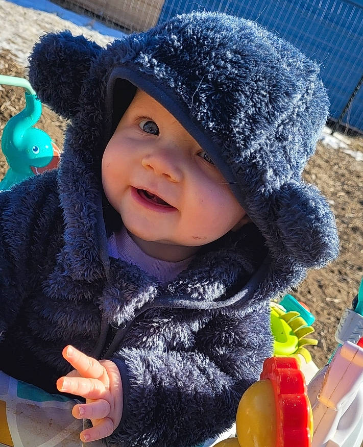 Addison is registered to the contest to win money with this photo: baby, baby_toddler_clothing, blue, cap, cheek, child, clothing, electric_blue, face, fun, happy, headwear, jacket, knit_cap, outerwear, person, plastic_bottle, skin, smile, toddler