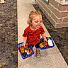 Zayaan joined the competition — help win amazing prizes! toddler, child, toy, shopping_basket, indoor, play_area, carpet, curly_hair, red_shirt, dinosaur_print, tongue_out, crawling_child, floor, wall, window, person, shoes, play, fun, smiling