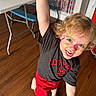 Zayaan is registered to the contest to win money with this photo: child, face_paint, smiling, barefoot, indoor, wooden_floor, table, bench, curtain, colorful, joyful, shorts, tshirt, blond_hair, playful, person, happy, raised_arm, decor, flooring