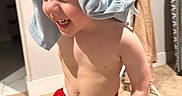 Zayaan is registered to the contest to win money with this photo: toddler, child, laughing, red_shorts, shirt_on_head, indoor, carpet, bare_chest, happy, playful, person, young_child, clothing, funny, smiling, home, cute, expression, casual, floor