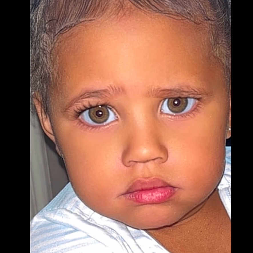 Anila is registered to the contest to win money with this photo: black_flower, child, close_up, curly_hair, cute, expression, eyes, face, fashion_accessory, hair_clips, head_and_shoulders, human, indoors, natural_light, person, portrait, serious, skin, white_shirt, young