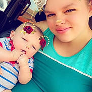 Blaine is registered to the contest to win money with this photo: baby, woman, selfie, car, flower_crown_filter, heart_overlay, smile, holding, casual_clothing, indoor, portrait, cute, child, family, love, affection, headshot, closeup, skin, people