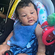 Harmoniee is registered to the contest to win money with this photo: baby, child, car_seat, blue_bib, blue_outfit, toy, curly_hair, car_interior, seatbelt, infant, child_seat, relaxed, cute, hand, leg, colorful, fabric, seat, sitting, portrait