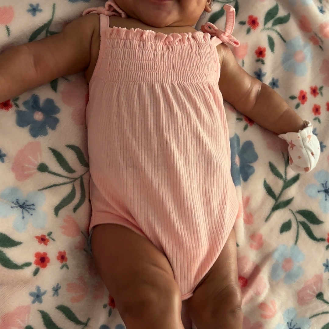 Harmoniee joined the competition — help win amazing prizes! arms, baby, blanket, child, cozy, cute, face, floral_pattern, happy, indoors, infant, legs, lying_down, mittens, pink_outfit, portrait, skin, smiling, soft_texture, young_child