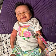 Harmoniee joined the competition — help win amazing prizes! baby, smiling, infant, clothing, shirt, shorts, pillow, purple, bed, blanket, pacifier_clip, rainbow, flower, face, person, cute, happy, indoors, child, toddler
