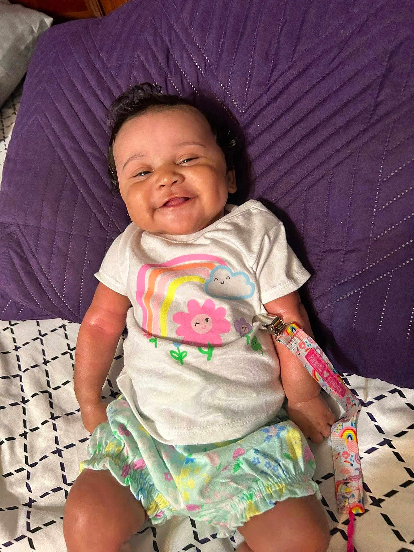 Harmoniee joined the competition — help win amazing prizes! baby, smiling, infant, clothing, shirt, shorts, pillow, purple, bed, blanket, pacifier_clip, rainbow, flower, face, person, cute, happy, indoors, child, toddler