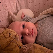 Pablo participe au concours pour gagner de l'argent avec cette photo : baby, infant, newborn, crib, bedding, blanket, plush_toy, stuffed_animal, pajamas, portrait, close_up, big_eyes, gaze, cozy, sleepy, soft_texture, stars_pattern, indoor, laying_down, face