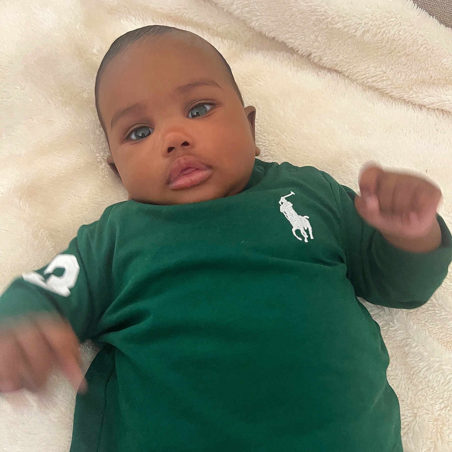 Yzaak a rejoint le concours — aidez-le/la à gagner de superbes lots ! baby, child, infant, blanket, green_shirt, polo_logo, long_sleeve, face, eyes, hands, jeans, lying_down, cute, expression, indoor, soft_texture, portrait, skin, person, closeup