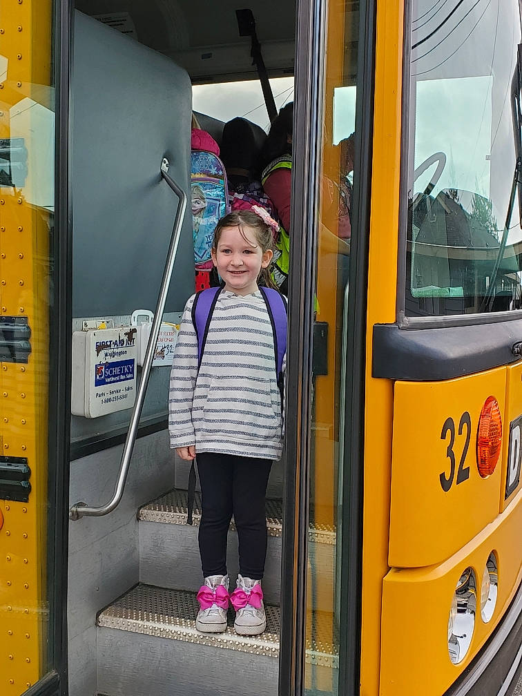 Bailee is registered to the contest to win money with this photo: automotive_exterior, bus, city, commercial_vehicle, door, double_decker_bus, gas, hat, joy, mode_of_transport, motor_vehicle, passenger, person, public_transport, smile, standing, toddler, tour_bus_service, travel, vehicle