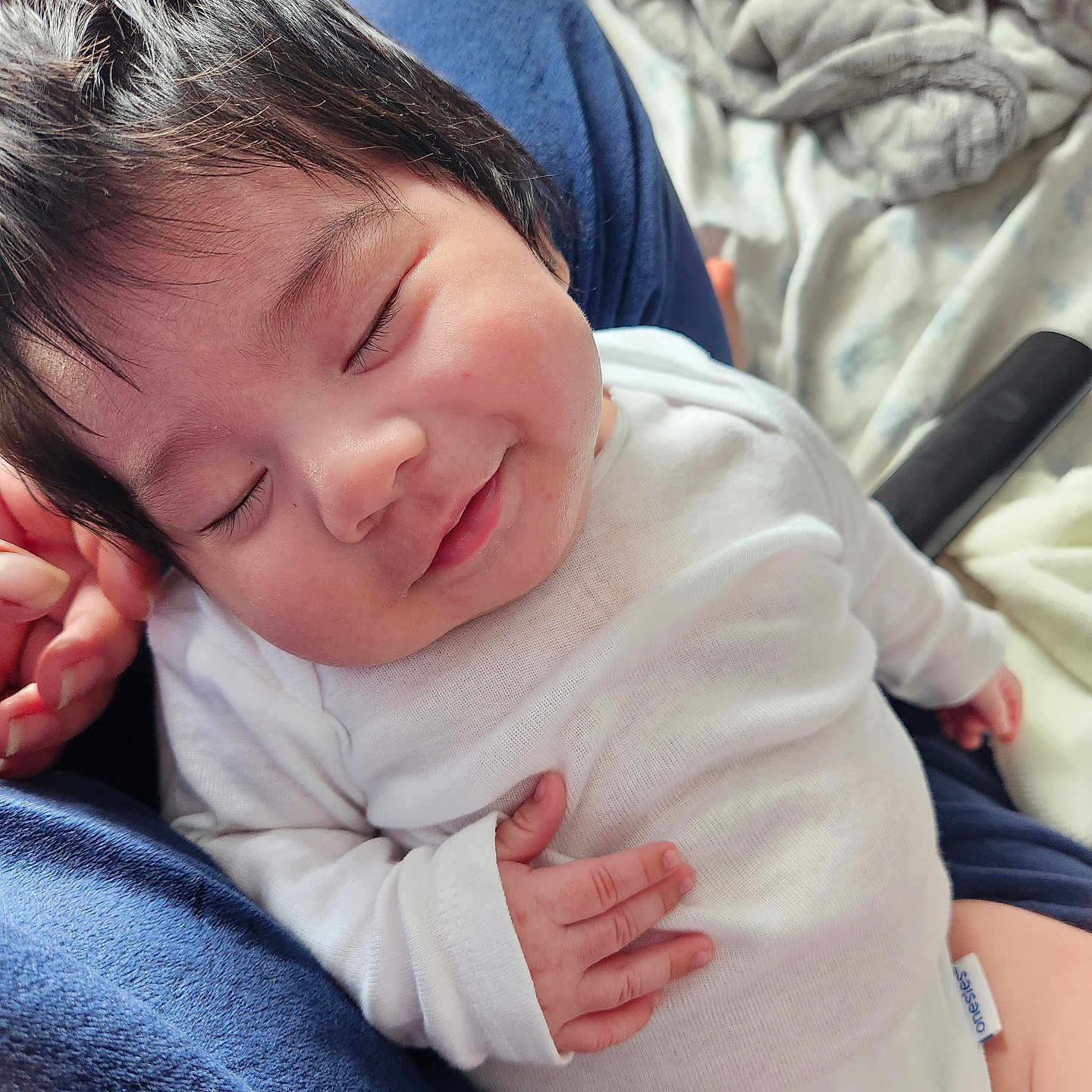 Nefertari joined the competition — help win amazing prizes! baby, bedding, blanket, closeup, cozy, cute, hand_on_chest, indoor, infant, lap, newborn, parent_hand, portrait, relaxed, sleeping, smiling, soft_texture, tiny_fingers, tousled_hair, white_onesie