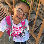Arianna is registered to the contest to win money with this photo: child, girl, glasses, green_bow, backpack, tshirt, sidewalk, stairs, concrete, outdoor, smiling, portrait, casual_clothing, young, happy, fashion_accessory, person, urban, daylight, playful