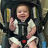 Andrew is registered to the contest to win money with this photo: baby, car_seat, smile, happy, infant, child, clothing, seatbelt, indoor, carrying_equipment, person, cute, waving, fabric, carpet, head, hand, footwear, protection, safety