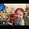 Andrew is registered to the contest to win money with this photo: child, toddler, smile, toy, wooden_toy, activity_cube, playroom, indoor, carpet, high_chair, baby, person, happy, furniture, colorful, play, floor, head, clothing, room