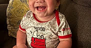Andrew joined the competition — help win amazing prizes! baby, smiling, child, onesie, snoopy, couch, pillow, blanket, indoor, happy, cute, portrait, infant, toddler, clothing, face, hand, hair, seated, cozy