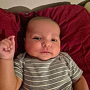 Jonas joined the competition — help win amazing prizes! baby, infant, child, portrait, face, eyes, smiling, hand, raised_hand, striped_shirt, clothing, pillow, bed, indoors, home, red, warm_lighting, sitting, closeup, photography