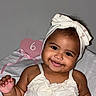 Mavie Ocean is registered to the contest to win money with this photo: adorable, baby, child, cute, face, hand, happy, headband, heart, indoors, infant, pink, portrait, sign, sitting, six_months, skin, smile, white_dress, young_child
