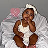 Mavie Ocean is registered to the contest to win money with this photo: baby, child, childrens_fashion, cute, dark_skin, fabric, finger_in_mouth, happy, headband, heart_sign, indoor, infant, pink_sign, portrait, sitting, six_months, smiling, soft_lighting, white_background, white_clothing