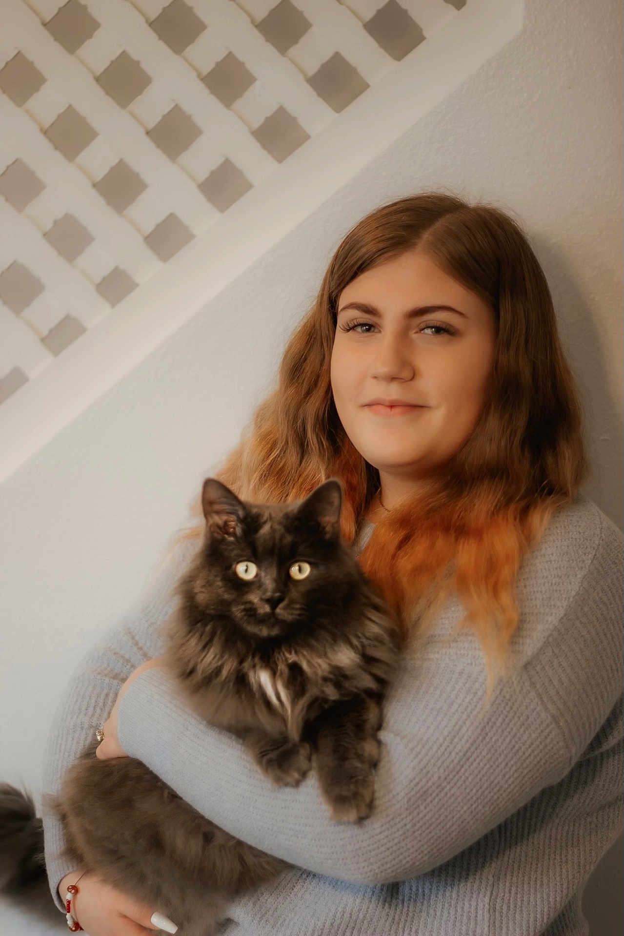 Smokey is registered to the contest to win money with this photo: woman, cat, indoor, portrait, fluffy_cat, long_hair, wavy_hair, omre_hair, gray_sweater, holding, pet, animal, feline, face, smile, warm_lighting, neutral_background, cozy, bond, cute