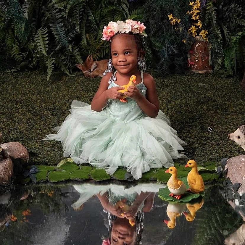 Dakotah is registered to the contest to win money with this photo: child, clothing, costume, dress, face, female, flower, girl, grass, head, nature, outdoors, person, petal, photography, plant, pond, portrait, pottedplant, water