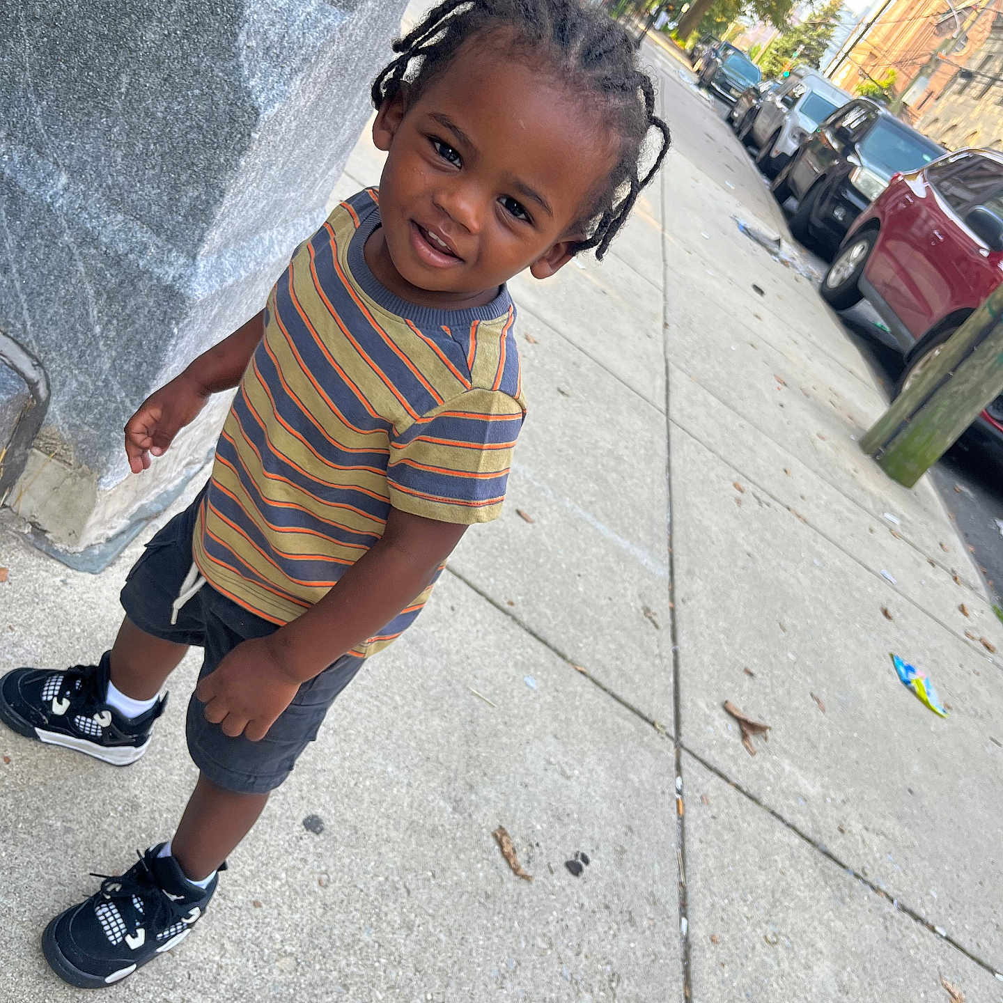 Noah joined the competition — help win amazing prizes! braids, building, cars, casual_clothing, child, concrete, curious, daylight, outdoor, person, shorts, sidewalk, smile, sneakers, street, striped_shirt, toddler, tree, urban, young