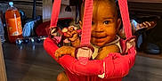 Love joined the competition — help win amazing prizes! baby, child, pink_jumper, indoor, smiling, floor, household_items, bottle, orange_soda, legs, feet, bandages, face, toy, flooring, doorway, storage, clutter, socks, hanging