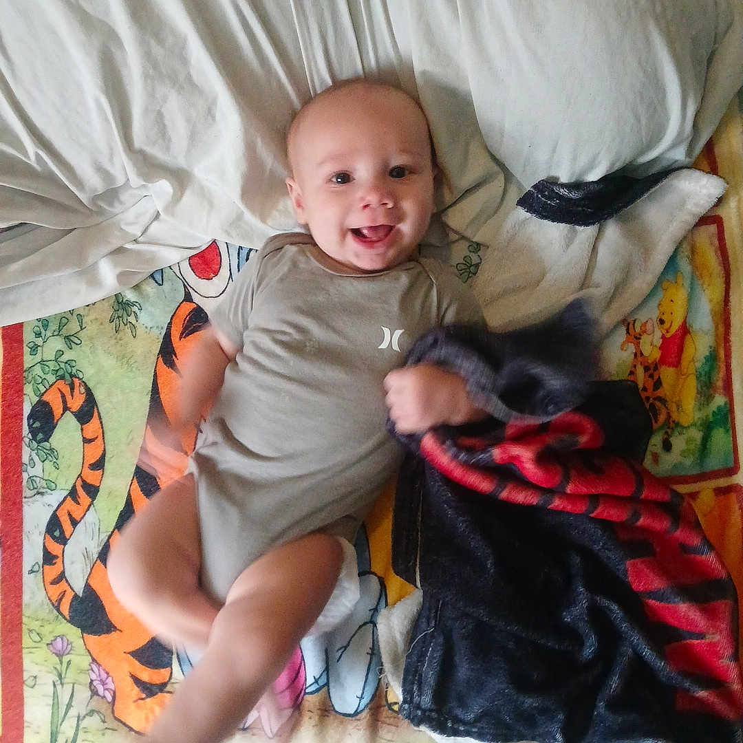 Erutan is registered to the contest to win money with this photo: baby, blanket, cartoon, child, clothing, cute, fabric, foot, hand, happy, indoors, infant, lying_down, motion_blur, person, pillow, playful, smiling, tiger, winnie_the_pooh