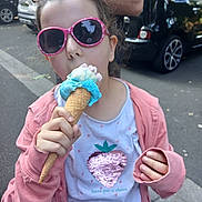 Lola a rejoint le concours — aidez-le/la à gagner de superbes lots ! child, girl, ice_cream, cone, sunglasses, pink_hoodie, white_shirt, strawberry_design, outdoor, sidewalk, car, person, summer, food, snack, hand, cool, casual_clothing, daylight, fun