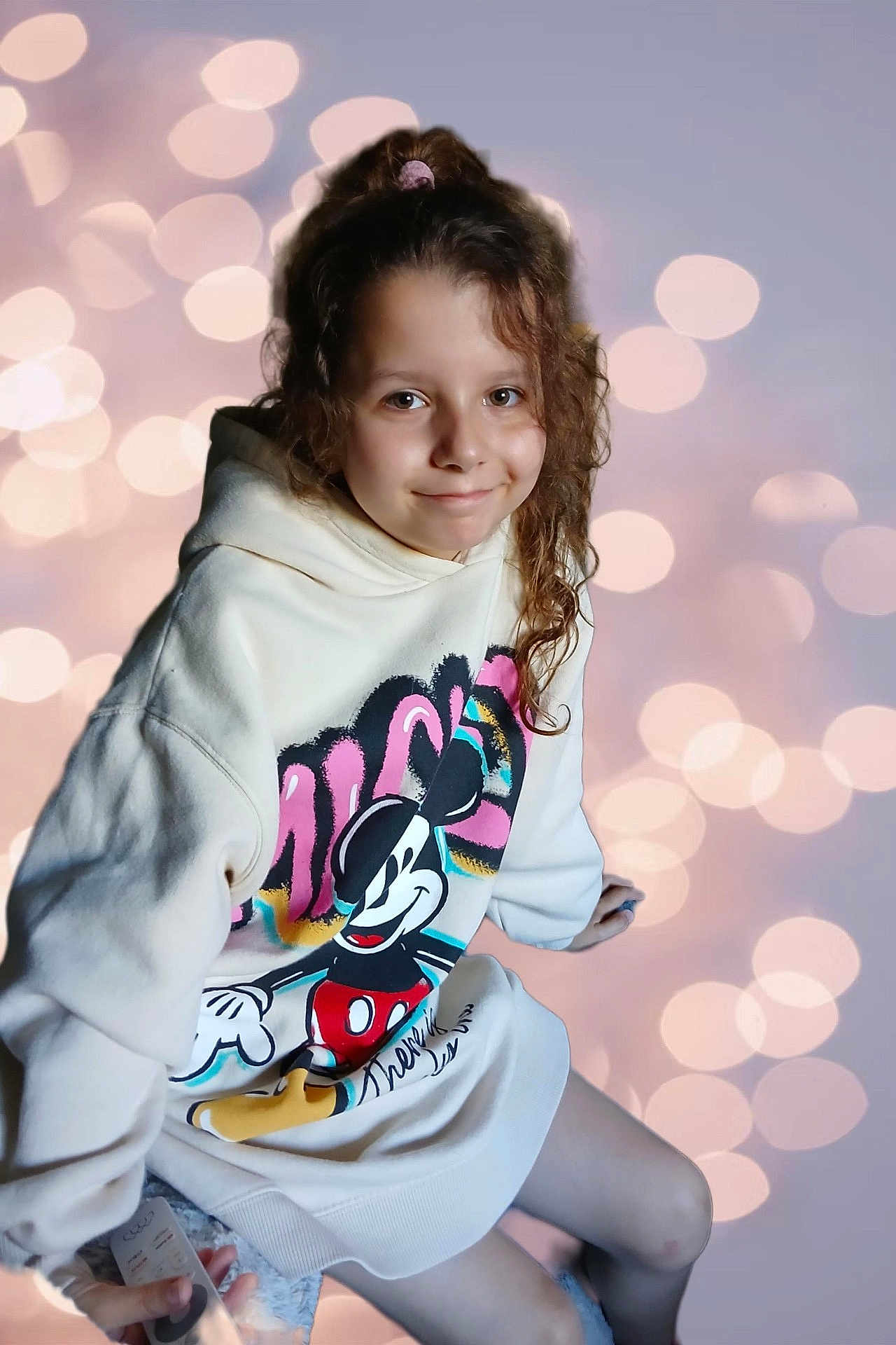 Lola participe au concours pour gagner de l'argent avec cette photo : child, girl, hoodie, mickey_mouse, curly_hair, scrunchie, smile, bokeh, lights, casual_clothing, portrait, young, sitting, indoor, cute, fashion, relaxed, happy, background, soft_lighting