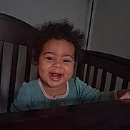 Gracie joined the competition — help win amazing prizes! toddler, child, crib, smile, curly_hair, pajamas, indoor, furniture, lamp, baby, happy, person, wooden, bedroom, face, young_child, home, cozy, standing, joyful