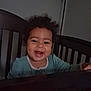 toddler, child, crib, smile, curly_hair, pajamas, indoor, furniture, lamp, baby, happy, person, wooden, bedroom, face, young_child, home, cozy, standing, joyful