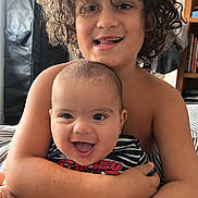 Evann participe au concours pour gagner de l'argent avec cette photo : baby, candid, child, closeup, curly_hair, cute, expression, family, happy, hugging, indoor, infant, joy, person, portrait, sibling, smiling, striped_clothing, toddler, warmth