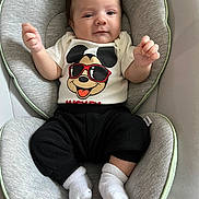 Luca joined the competition — help win amazing prizes! baby, infant, mickey_mouse, shirt, black_pants, white_socks, cushion, seat, soft_fabric, smiling, face, child, indoors, comfortable, clothing, cute, young, person, relaxing, baby_seat