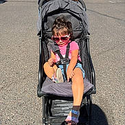 Nataly joined the competition — help win amazing prizes! child, denim_shorts, face, hair, harness, heart_shaped_sunglasses, outdoor, parent, parked_cars, parking_lot, pavement, pink_shirt, portrait, sandals, seated, stroller, sunglasses, sunlight, toddler, topknot
