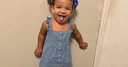 Nataly is registered to the contest to win money with this photo: bear_slippers, blue_dress, braids, casual_clothing, child, door, full_body, girl, hair_bows, home, indoor, playful, portrait, slippers, smiling, standing, toddler, tongue_out, wall, wood_floor