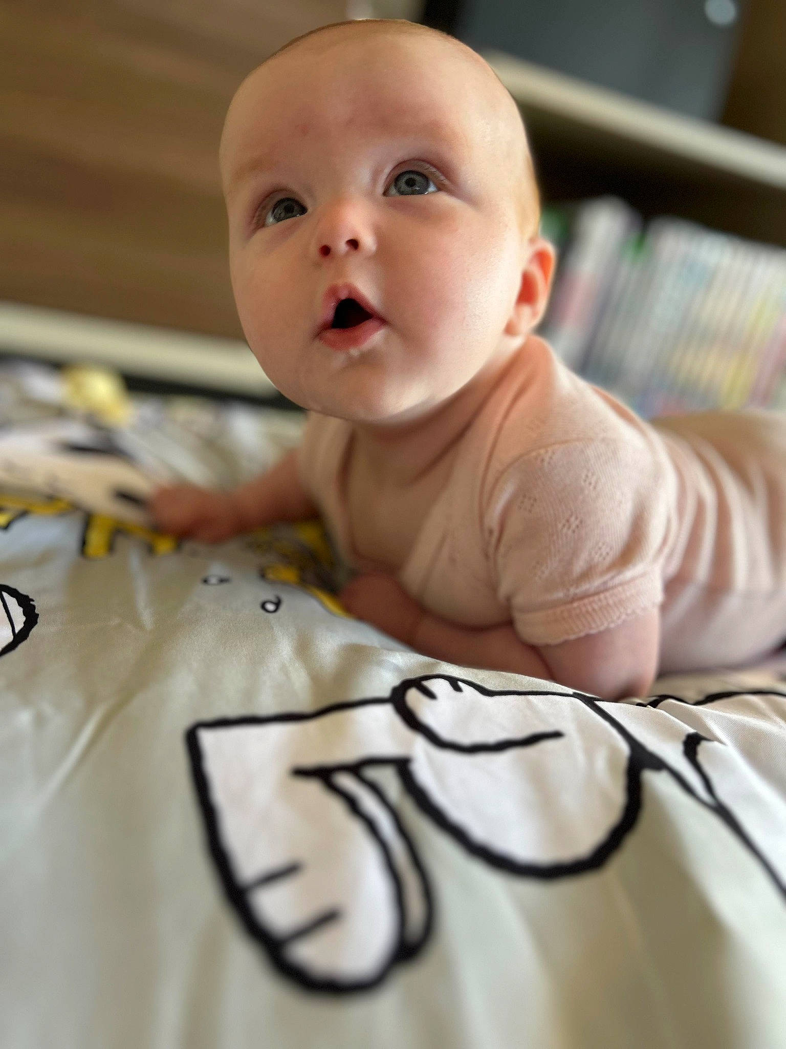 Vienna is registered to the contest to win money with this photo: arm, baby, baby_toddler_clothing, cheek, child, comfort, eyebrow, face, flooring, hardwood, head, linens, pattern, person, room, sitting, sleeve, surprise, t_shirt, textile