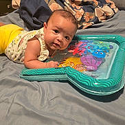 Maddie joined the competition — help win amazing prizes! baby, infant, bed, blanket, pillow, toy, inflatable, water_mat, curious, lying_down, indoor, home, soft, colorful, child, person, face, clothing, yellow_pants, white_shirt
