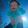 baby, child, blue_sky, sunlight, mittens, fleece, joyful, outdoor, winter, trees, smiling, hands, holding, hood, portrait, person, happy, bright, sunflare, nature