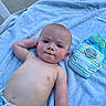 Echo is registered to the contest to win money with this photo: baby, child, towel, diaper, swim_diaper, outdoor, sunlight, blue, skin, bare_chest, face, expression, curious, laying, person, infant, summer, relaxing, clothing, cute