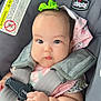 baby, infant, child, car_seat, safety_harness, bow, pink_clothing, cute, chubby_cheeks, hand, face, eyes, expression, indoor, photography, child_safety, seat_belt, person, closeup, car