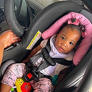 Jazlynn joined the competition — help win amazing prizes! baby, car_seat, child, infant, toy, pink, bow, curly_hair, seatbelt, hand, car_interior, clothing, cute, face, sitting, portrait, safety, young_child, looking_up, indoor