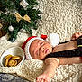 élio participe au concours pour gagner de l'argent avec cette photo : baby, sleeping, santa_hat, knitted_clothing, blanket, christmas_tree, cookies, bowl, holiday, decorations, indoor, cozy, child, infant, toddler, face, hand, festive, cute, relaxing