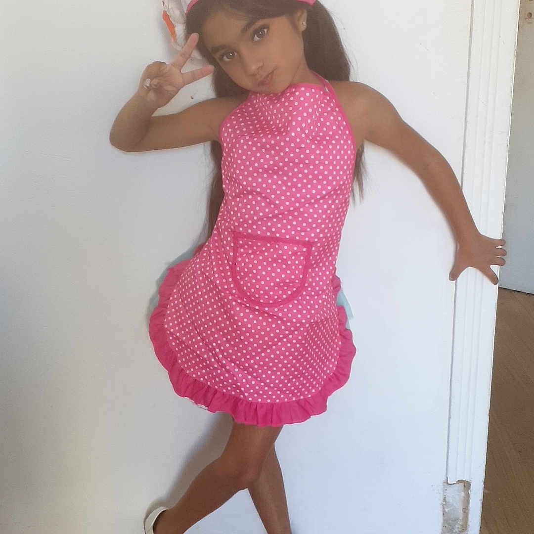 Tahicyana participe au concours pour gagner de l'argent avec cette photo : bows, casual, chef_hat, child, cute, fashion, girl, indoor, long_hair, peace_sign, person, pink_apron, playful, polka_dot, portrait, pose, smile, white_shoes, white_wall, wooden_floor