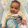 baby, infant, smile, baby_seat, clothing, cute, child, happy, indoors, face, hand, patterned_clothes, seatbelt, plush, comfort, portrait, young_child, baby_toys, playful, colorful