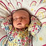 baby, sleeping, floral_clothing, blanket, rainbow_pattern, infant, peaceful, closed_eyes, cute, soft_texture, pajamas, child, resting, cozy, portrait, indoors, comfort, newborn, head, face