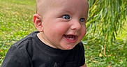 Nolan joined the competition — help win amazing prizes! baby, black_shirt, blue_eyes, child, cute, daylight, grass, greenery, happy, infant, nature, outdoor, park, person, portrait, shorts, sitting, smiling, sunlight, young