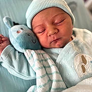 Aaron participe au concours pour gagner de l'argent avec cette photo : baby, blanket, childbirth, clothing, doll, face, hat, head, newborn, person, photography, portrait, sleeping, toy