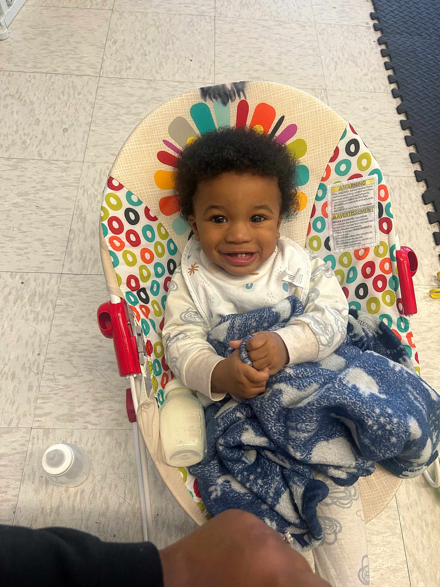 Kajun joined the competition — help win amazing prizes! baby, child, smiling, curly_hair, blanket, bottle, baby_chair, colorful, floor, indoor, happy, person, infant, clothing, toy, patterned, seat, baby_bottle, blanket_pattern, floor_tiles