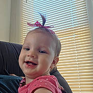 Susan joined the competition — help win amazing prizes! baby, child, toddler, smiling, portrait, indoor, pink_bow, hair_bow, pink_clothing, heart_pattern, face, teeth, sitting, chair, window, blinds, sunlight, close_up, happy, photography